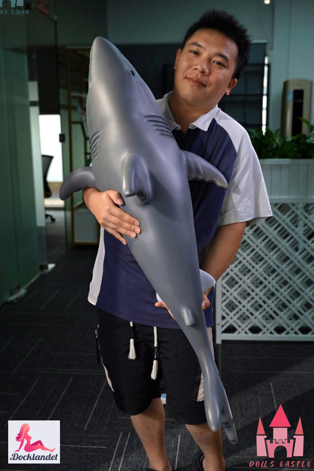 Shark Doll 110 cm est tenu dans les bras pour montrer la taille et les proportions, design de requin réaliste avec haut gris et bas blanc.