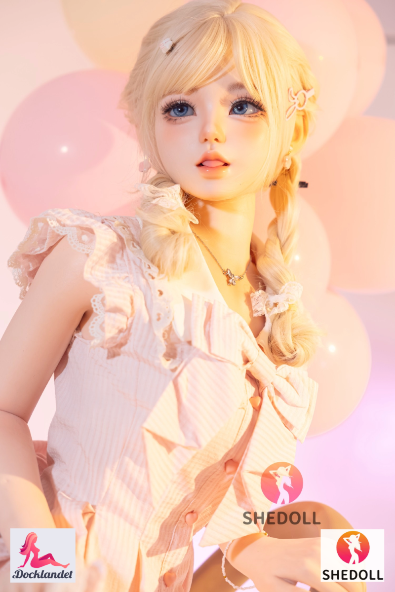 Sandy SHEDOLL 152 cm A-kupa, närbild med blont hår i flätor och rosa klänning, ballonger i mjuk studiobelysning.